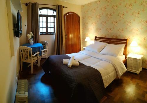 - une chambre avec un grand lit et une fenêtre dans l'établissement Refúgio das Rosas, à Campos do Jordão
