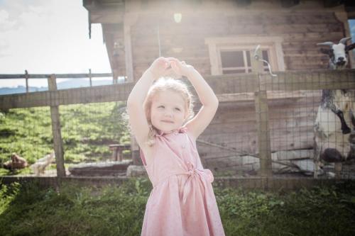 a little girl in a pink dress standing in front of a house at Hotel AlpenSchlössl in Sankt Johann im Pongau