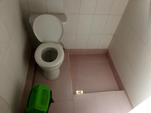 La petite salle de bains est pourvue de toilettes et d'un tabouret vert. dans l'établissement Las Cabañas Lodge, à Isla de Sol