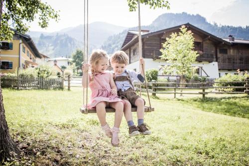 two children sitting on a swing in a yard at Hotel AlpenSchlössl in Sankt Johann im Pongau