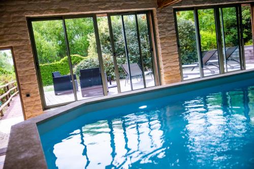 a swimming pool in a house with windows at La Ferme de L'Oudon & SPA in Berville