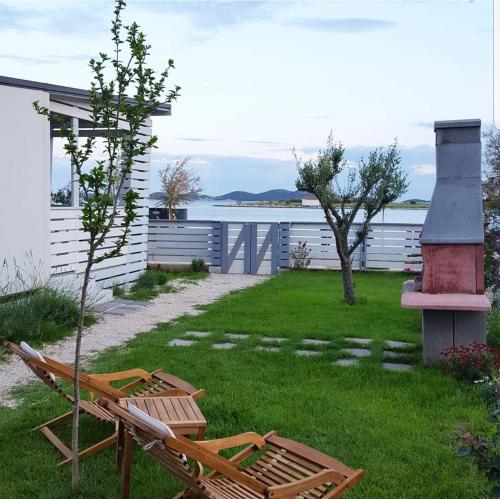 - deux chaises assises sur l'herbe près d'une maison dans l'établissement Rasin Mobile Homes, à Pakoštane