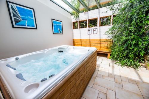 - une grande baignoire dans une pièce ornée de plantes dans l'établissement La Ferme de L'Oudon & SPA, à Berville