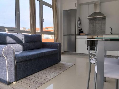 uma sala de estar com um sofá azul e uma cozinha em Apartamento en Ribeira(centro) 3* planta em Ribeira