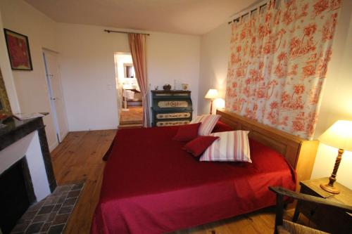 a bedroom with a red bed with pillows on it at Le Pommenial de la Hérissonnière in Saint-Aubin-de-Bonneval