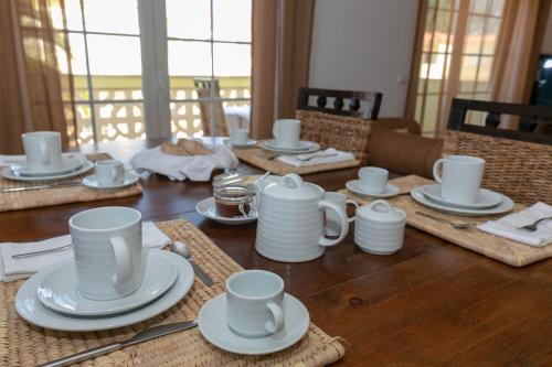 a wooden table with white cups and saucers on it at Apartment - Golf & Beach Resort in Casal da Lagoa Seca
