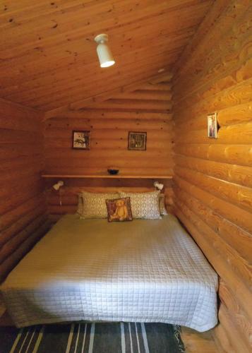 a bed in a cabin with wooden walls at Pankkotupa Yrjo in Punkaharju