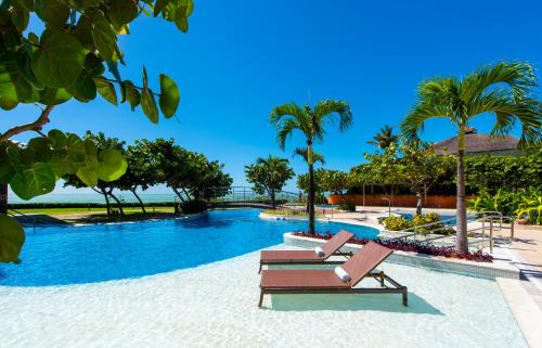 a resort pool with two lounge chairs and palm trees at Vogal Luxury Beach Hotel & SPA in Natal