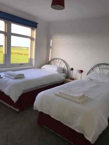 2 Betten in einem Zimmer mit Fenster in der Unterkunft Ayrshire cottage in Kilmarnock