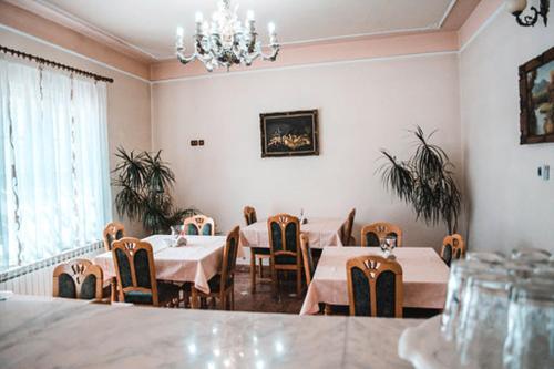 a dining room with tables and chairs and a chandelier at Pensiunea Ana in Baile Felix