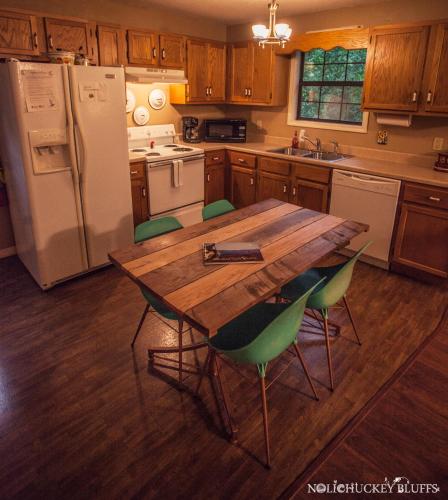 a kitchen with a wooden table and green chairs at Nolichuckey Bluffs Bed & Breakfast Cabins in Greeneville