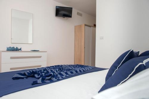 a bedroom with a bed with blue sheets and a tv at Al Faro Guest House in Vieste