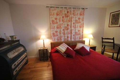 a bedroom with a red bed with two pillows on it at Le Pommenial de la Hérissonnière in Saint-Aubin-de-Bonneval