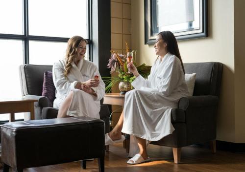 two women in white robes sitting around a table at Temple Gardens Hotel & Spa in Moose Jaw