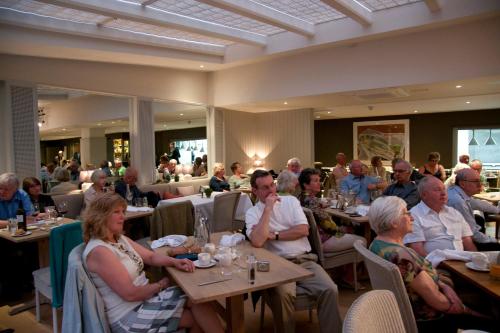a group of people sitting at tables in a restaurant at The Hoste and The Vine House Hotels in Burnham Market