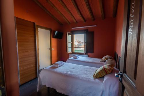 two beds in a room with orange walls and a window at La Casa Azul in Alcanadre