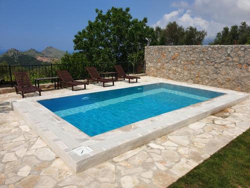 a swimming pool with chairs and a stone wall at Apartman Nikocevic in Dobra Voda