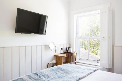 a bedroom with a bed and a television on the wall at Hotel Continental in Whitstable