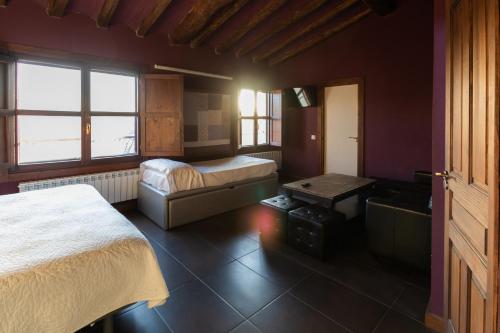 a bedroom with two beds and a table and windows at La Casa Azul in Alcanadre