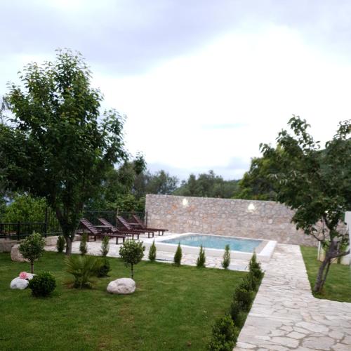 a backyard with a swimming pool and chairs and trees at Apartman Nikocevic in Dobra Voda