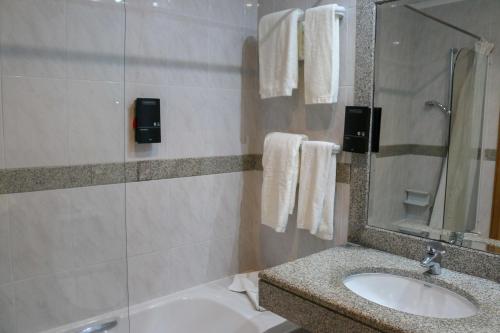 a bathroom with a sink and a tub and a mirror at Hotel Horta in Horta