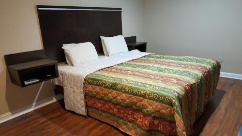 1 dormitorio con 1 cama con manta y mesita de noche en ACE Motel, en Pasadena