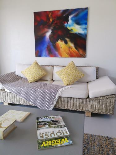 a living room with a couch and a painting on the wall at Three Feathers Cottages in Langebaan