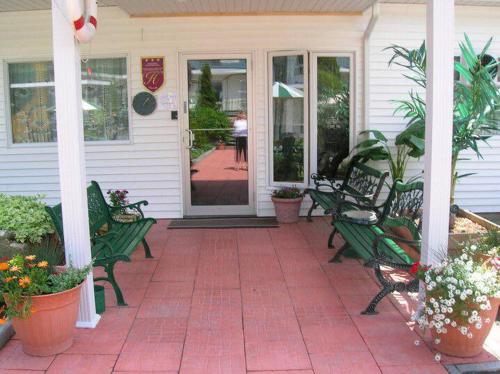 a porch with green benches in front of a house at Hotel-Motel Les Voitures d'Eau in L'Isle-aux-Coudres