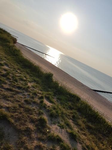 a beach with the sun rising over the water at Pokoje gościnne u Laury in Rewal