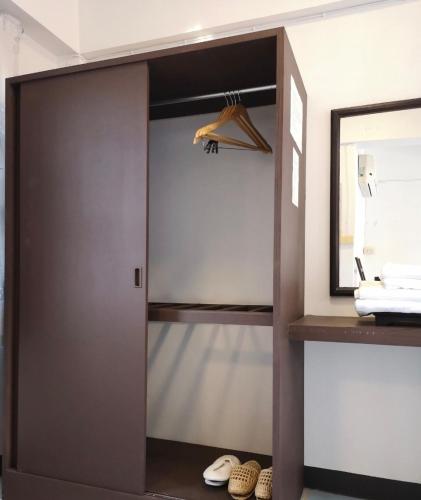 a closet with a door and a mirror and shoes at RoongThoeng Place Hotel in Thoeng