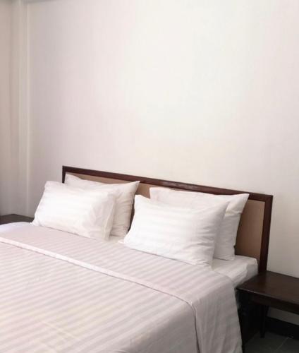 a bed with white sheets and pillows on it at RoongThoeng Place Hotel in Thoeng