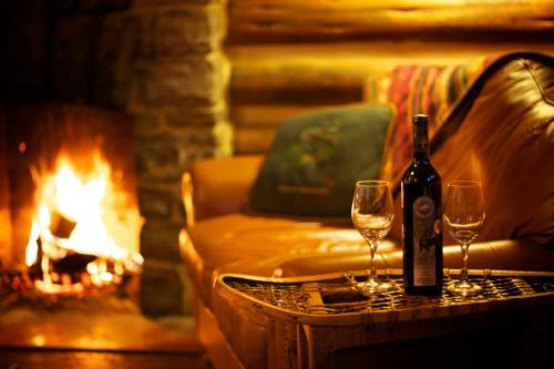 a bottle of wine and two glasses on a table next to a fireplace at Storm Mountain Lodge & Cabins in Banff