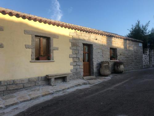 a stone building with two windows and a bench outside at Li Cimi in San Pantaleo