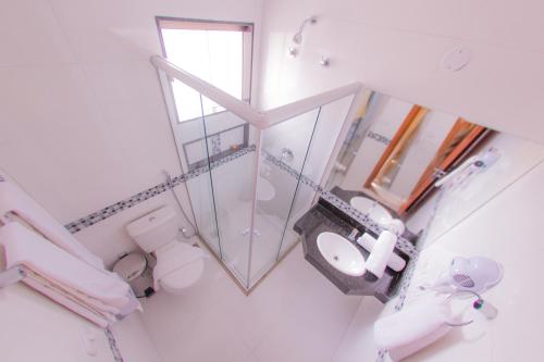 a bathroom with a mirror and a toilet and a sink at Safira Praia Hotel in Porto Seguro