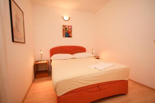 a small bedroom with a bed with a red headboard at Apartments Garden in Orebić