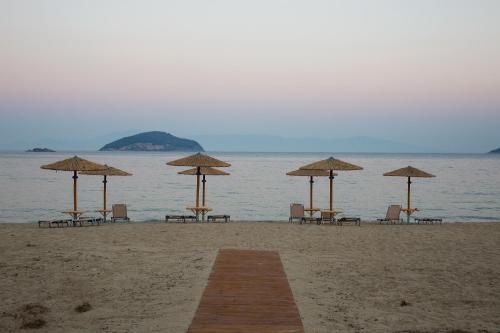 a group of chairs and umbrellas on a beach at Rent House Karavi in Iraklitsa