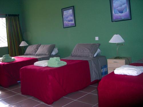 a bedroom with two beds and a green wall at Jamaica Inn Guest House in Botianaw