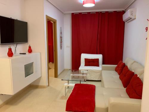 sala de estar con sofá blanco y TV en Apartamentos Marina Dor Agua Marina en Oropesa del Mar