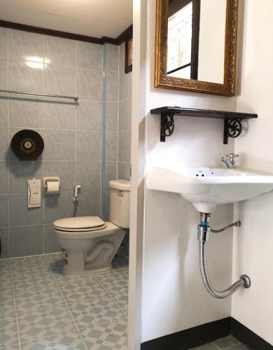 a bathroom with a toilet and a sink and a mirror at RoongThoeng Place Hotel in Thoeng