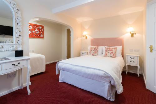 a bedroom with a large white bed and a mirror at The Old Fourpenny Hotel in Warwick