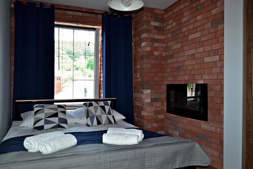 um quarto com uma cama com cortinas azuis e uma parede de tijolos em Apartament Uśmiech em Ustrzyki Dolne