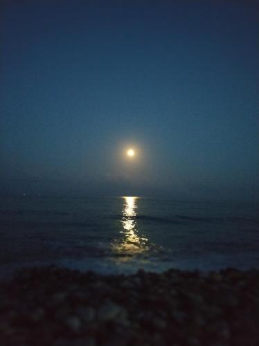 a full moon rising over the ocean at night at Agios Andreas Beach Villas in Áyios Andréas Messinias