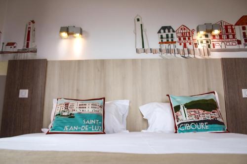 a bed with two pillows on top of it at Hotel Agur Deneri in Ciboure