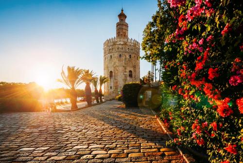 einen Uhrturm auf einer Kopfsteinpflasterstraße mit Blumen in der Unterkunft Pensión La Montoreña in Sevilla