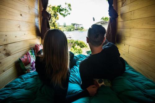 two people sitting on a bed looking out a window at Chili Kiwi Lakefront Backpackers in Pucón