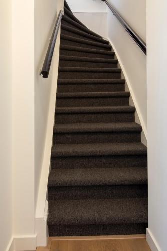 a staircase with black treads and white walls at Seapoint - Sea view in Zandvoort