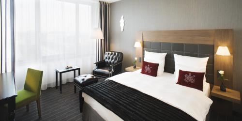 a hotel room with a bed and a chair at Mövenpick Hotel Stuttgart Airport in Stuttgart