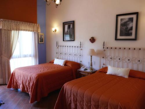 a bedroom with two beds and a window at El Meson de los Poetas in Guanajuato