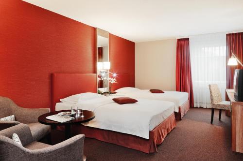 a hotel room with two beds and a table and chairs at Mövenpick Hotel Egerkingen in Egerkingen