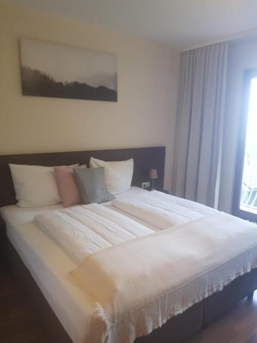 a large white bed in a bedroom with a window at Weltmann`s Hotel & Restaurant in Ennepetal